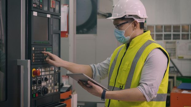 Asian factory worker man operating automated programming CNC milling control machine industry center at tool workshop manufacturing