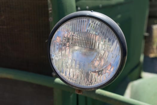 Old car headlight on a green background.