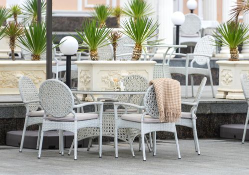 white wicker rattan furniture on the street outside the building.
