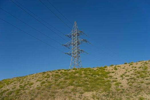 electric tower with wires on the hill against the blue sky.