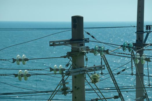 high voltage power line against the blue sea and clear sky