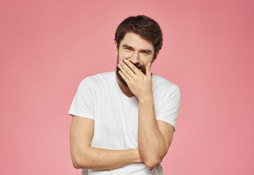 A man on a pink background with a thick beard gestures with his hands. High quality photo