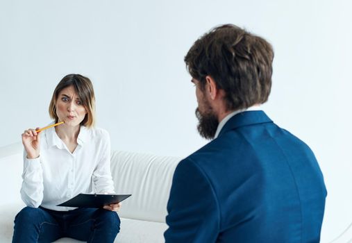 Business man in a classic suit and a woman on the couch with documents in the hands of a psychologist . High quality photo