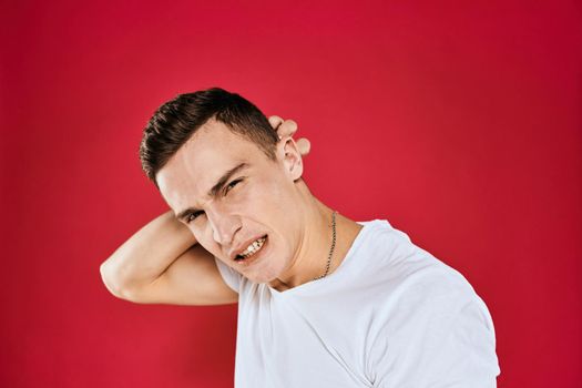 Emotional man white t-shirt displeased facial expression red isolated background cropped view. High quality photo
