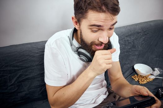 cheerful man sitting on the couch playing entertainment technology. High quality photo