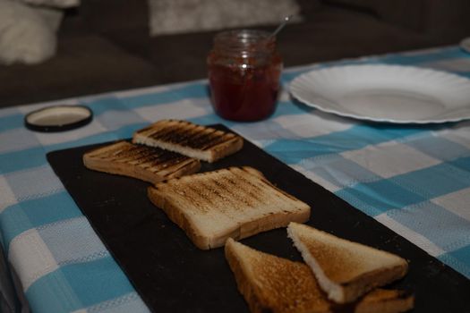 Toasted bread board with jams and a pretty blue and white tablecloth