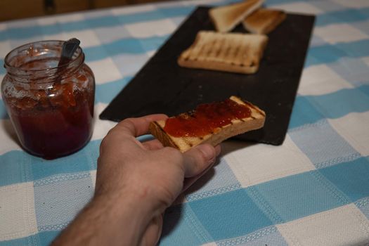 Hand clutching a piece of toast with jam