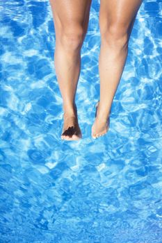 Slim legs of young woman in swimming pool. Summer time