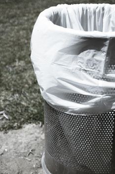 Trash bin in a park with white plastic bag. No people