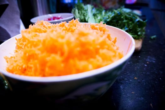Bowl full of fresh grated carrot. No people