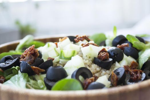 Quinoa, lettuce, lambs lettuce, black olives and cucumber salad. No people