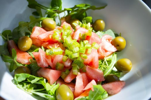 Arugula salad with tomato olives and pickles. No people