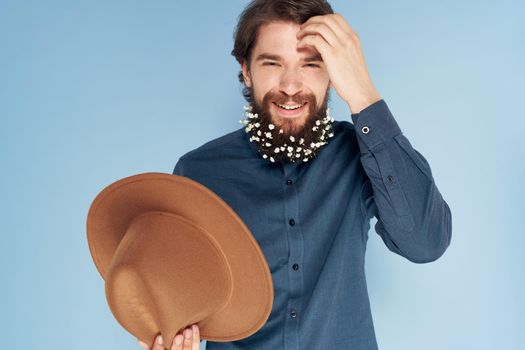 man in shirt flowers in beard hat emotions elegant style blue background. High quality photo