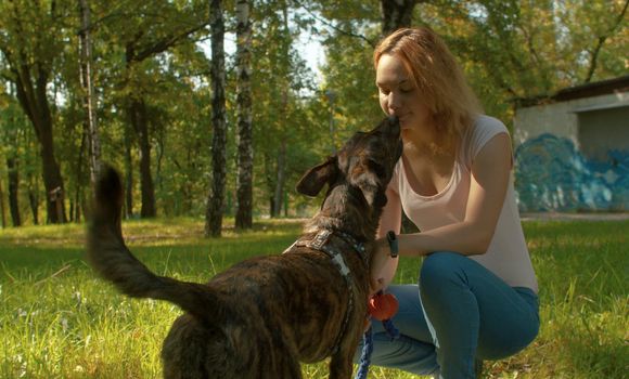 Best friends - handsome lady and her clever dog on the grass among the trees