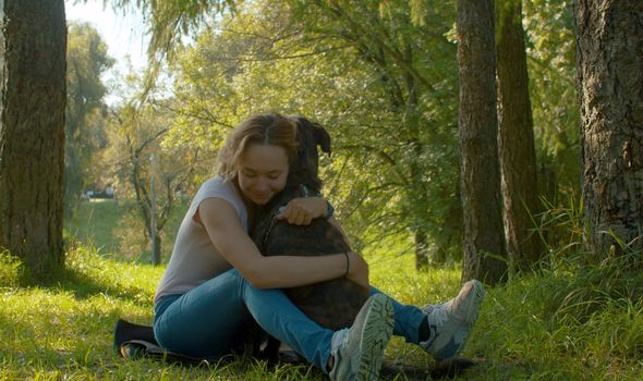 Attractive smiling woman hugging her nice dog. Young attractive lady and her dog on the stroll in the park.