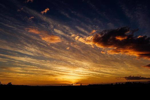 Natural Sunset Sunrise Over Field Or Meadow. Bright Dramatic Sky And Dark Ground. Countryside Landscape Under Scenic Colorful Sky At Sunset Dawn Sunrise. Sun Over Skyline, Horizon. Warm Colours.