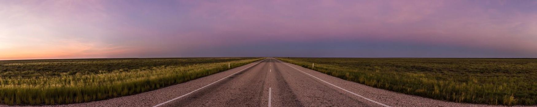 panorama of a straight road through the outback of Australia, after a beautiful sunset