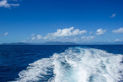 beautiful wake wave behind a big boat for tourist diving at the great barrier reef with blue montains in the background, cairns, australia
