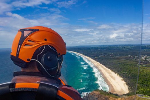 head of a pilot in a Gyrocopter with Wategoes Beach in the background, Byron Bay, Queensland, Australia.