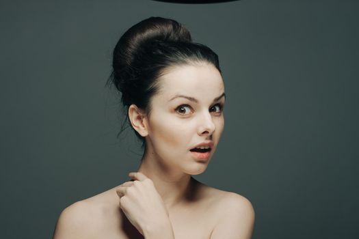 brunette with bare shoulders gathered hair hand near face. High quality photo