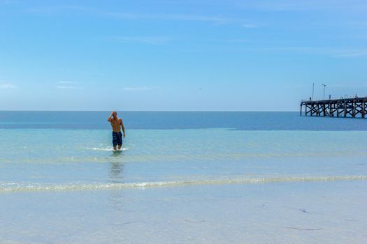 A Man walking out of water on a Tropical White Sand Beach of Western Australia