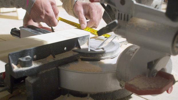 Close up hands of carpenter measuring a plank using roulette