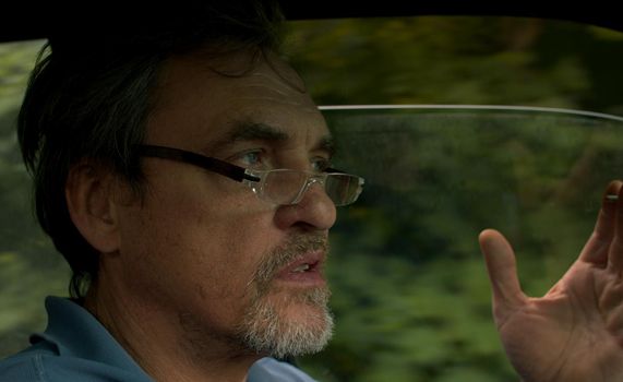 Close up portrait of handsome senior man driving a car. Shooting inside the car