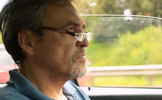 Close up portrait of handsome senior man driving a car. Shooting inside the car