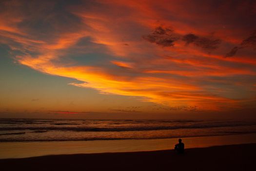 Young man sitting outdoors watching the sunset. Thinking and relaxing concept.