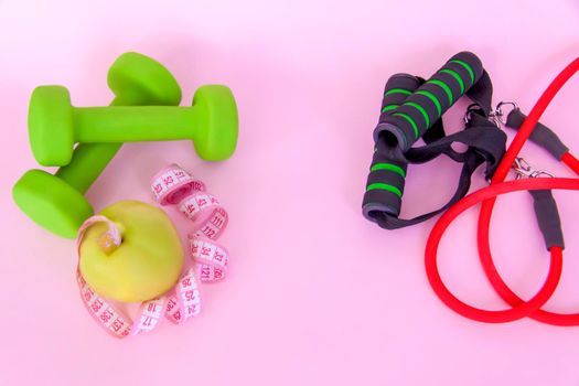 A green apple, and a centimeter measuring tape on a pink background. Sports, sports nutrition, healthy eating, diet. Space for the text. Exercise, lose weight 