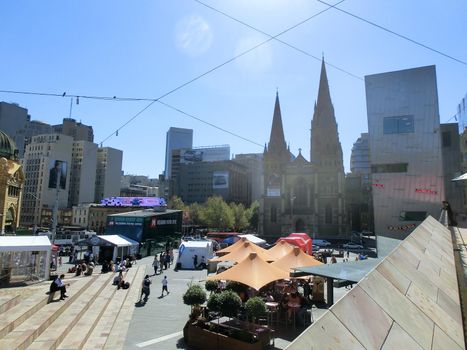Federation Square and St. Paul's Cathedral in downtown Melbourne on a sunny day. Its a popular place for tourists and local people