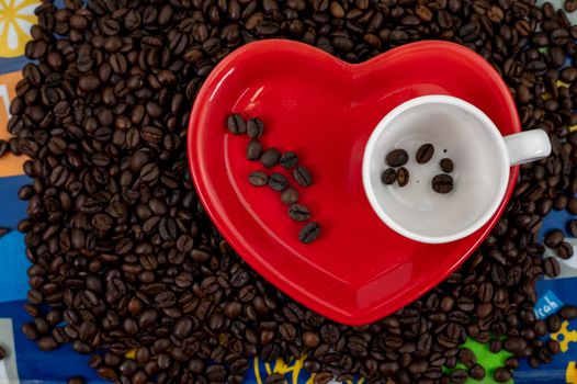 coffee grain composition in heart shape background with cup and saucer