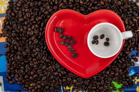 coffee grain composition in heart shape background with cup and saucer