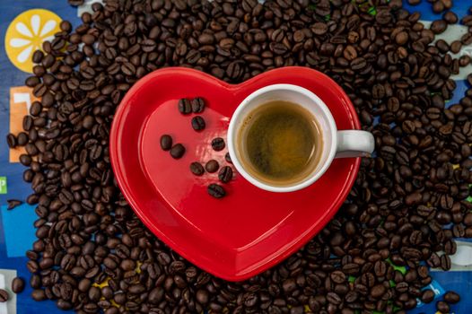 coffee grain composition in heart shape background with cup and saucer