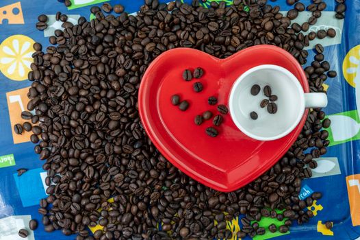 coffee grain composition in heart shape background with cup and saucer