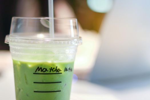 Iced matcha green tea latte on table with women working in store.