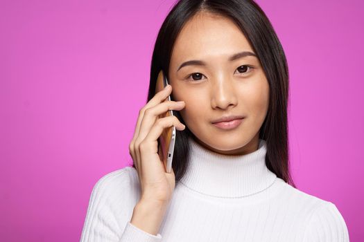 cheerful pretty brunette talking on the phone cropped view pink background. High quality photo