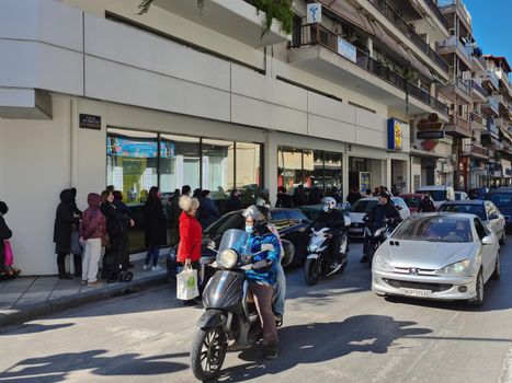 Large number of people with face protection wait in line to enter LIDL Stiftung German discount store.