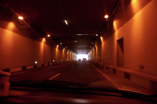 car driving through tunnel. highway tunnel with light at the end.