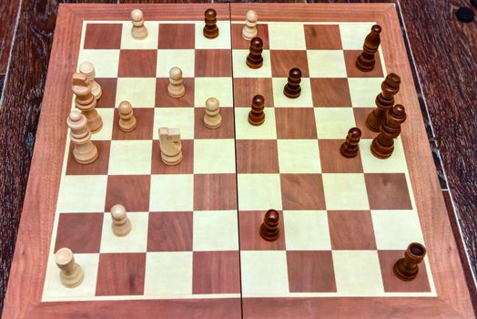 White and black chess pieces stand on board during a chess game. top view.