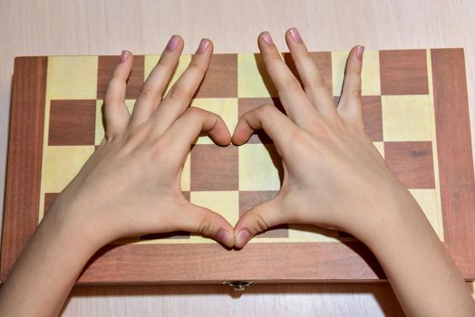 the child's hands on the chessboard show the heart and love of playing chess.