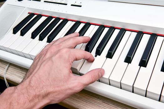 Close-up of the hand of a musical artist playing the piano, a man's hand, classical music, keyboard, synthesizer, pianist.