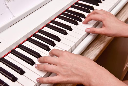 Woman's hands playing electronic digital piano at home. The woman is professional pianist arranging music using piano electronic keyboards. Musician practicing keyboard composing music.