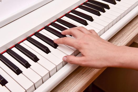 Woman's hands playing electronic digital piano at home. The woman is professional pianist arranging music using piano electronic keyboards. Musician practicing keyboard composing music.