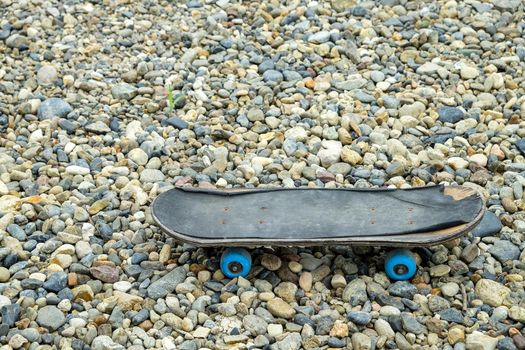 old skateboard stands on small colored pebbles.