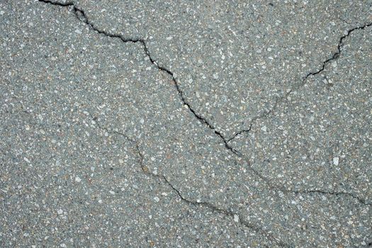 Cracked asphalt in the city, cracks and potholes on the road, textured road surface.