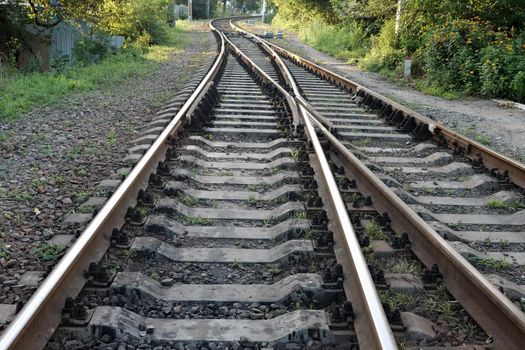 Fragment of a railway track with rails and sleepers in the countryside.