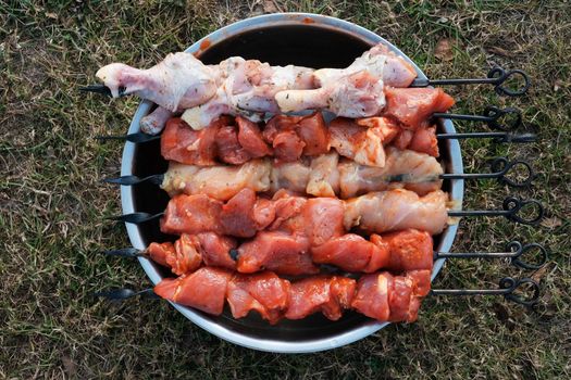 Raw pork skewers and chicken thighs, cut into pieces. meat on grill skewers. outdoor cooking on a picnic trip. top view.