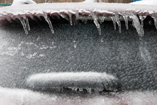 Ice covered car window close up. Car covered with ice and icicles after freezing rain. wiper covered with ice, ice storm.