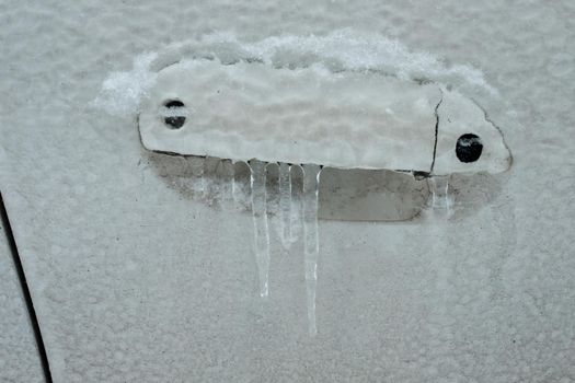 Frozen car door closeup, icicles, ice crystals, jammed lock.